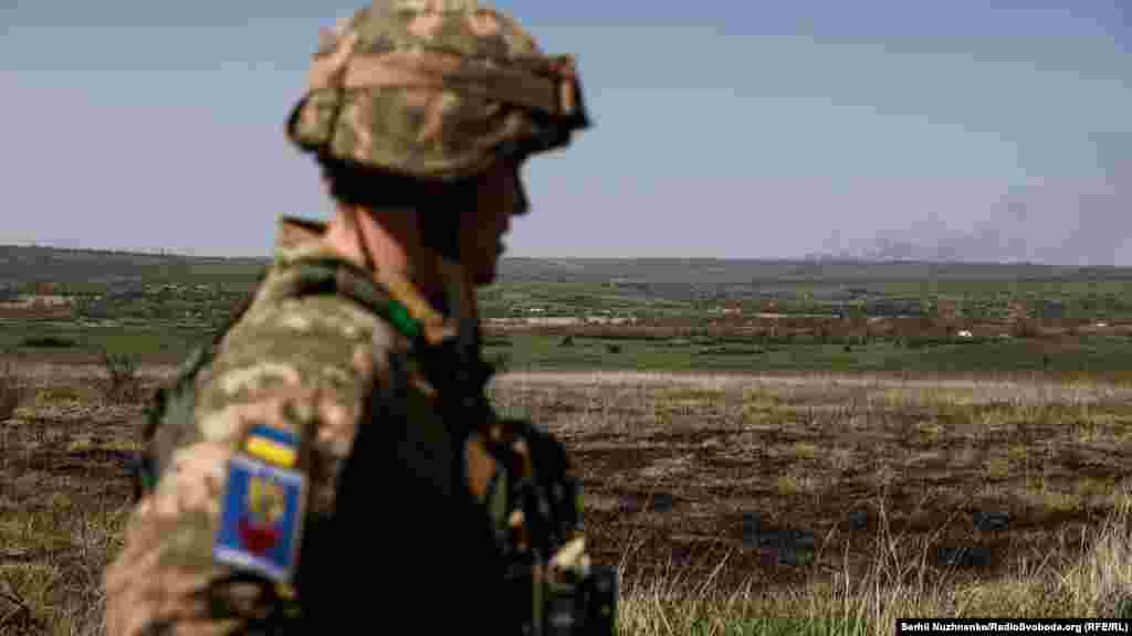 Український військовий дивиться на дим, який підіймається після обстрілу російських військ. Луганська область, 26 квітня 2022 року