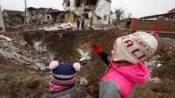 UKRAINE – Kids stand next to a crater left by a Russian missile strike, amid Russia's attack on Ukraine, in the town of Hlevakha, outside Kyiv, January 26, 2023