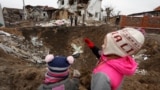 UKRAINE – Kids stand next to a crater left by a Russian missile strike, amid Russia's attack on Ukraine, in the town of Hlevakha, outside Kyiv, January 26, 2023