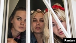 Три задержанные активистки FEMEN выглядывают из окна суда в Киеве. 28 июля 2013 года