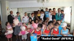 Tajikistan,Dushanbe city, a tajik participant in London Oympic -2012 presenting a gift to a scholol children,18July,201