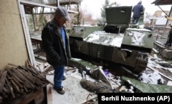 Чоловік дивиться на тіло російського військовослужбовця, що лежить біля військової машини після того, як бійці ЗСУ розгромили противника в місті Буча, що неподалік від Києва, 1 березня 2022 року