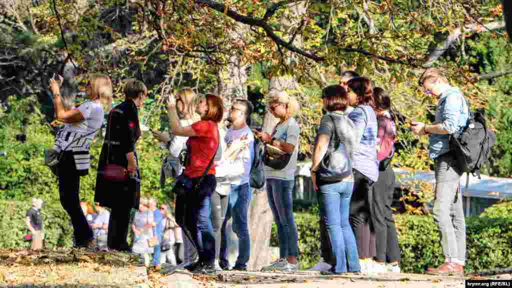 Організована екскурсійна група слухає розповідь гіда і фотографує