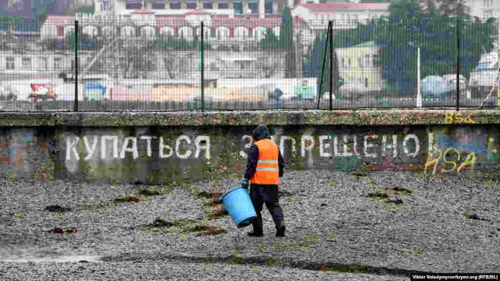 Прибиральник збирає водорості на міському пляжі